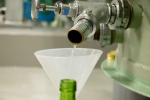 秘蔵熟成古酒もろはくの貯蔵タンクの呑口が切られ、用意された瓶に少量注がれていく